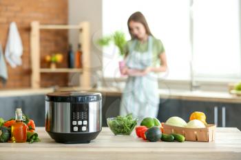 Modern multi cooker and products on kitchen table�