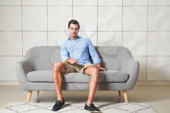 Stylish man sitting on sofa indoors�