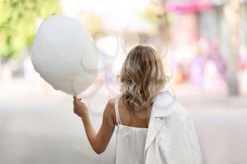 Woman with sweet cotton candy outdoors, back view�
