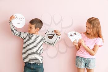 Little children with drawn emoticons on color background�