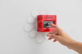 Woman using manual call point of fire alarm system�
