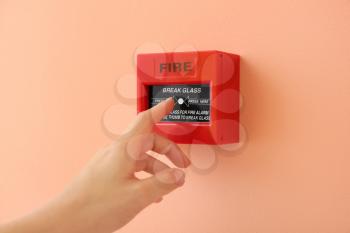 Woman using manual call point of fire alarm system�