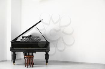 Black grand piano near white wall in empty room�