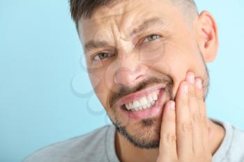 Man suffering from toothache against color background, closeup�