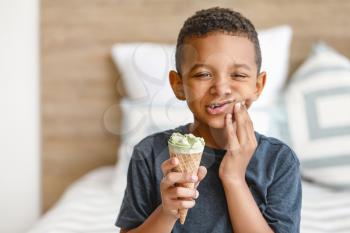 Little African-American boy with sensitive teeth and cold ice-cream at home�