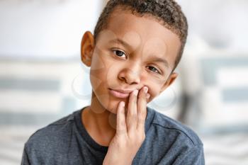 Little African-American boy suffering from toothache at home�