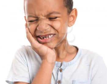 Little African-American boy suffering from toothache against white background�