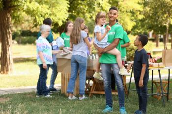 African-American volunteer with poor little children outdoors�