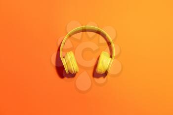 Modern headphones on color background�