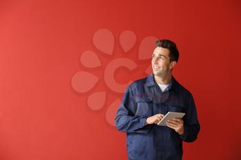 Male car mechanic with tablet computer on color background�