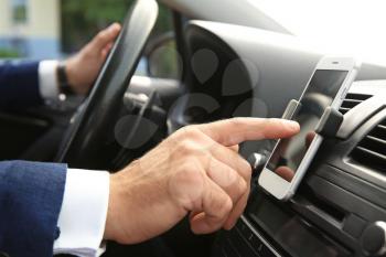 Businessman using mobile phone for navigation while driving car, closeup�