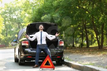 Stressed businessman near broken car outdoors�