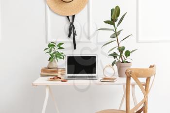 Stylish workplace with modern laptop near white wall�