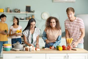 Happy friends cooking together in kitchen�