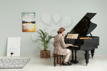 Man playing grand piano at home�