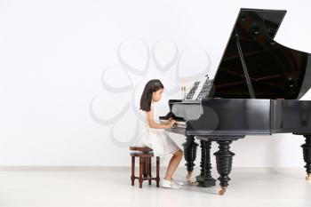 Little girl playing grand piano at home�