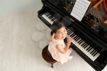 Little girl playing grand piano at home, top view�