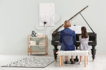 Man teaching little girl to play piano�