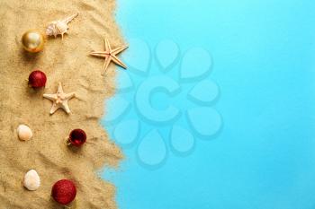 Beach sand with Christmas balls on color background�