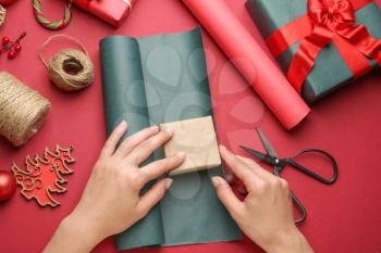 Woman making Christmas gift on color background�