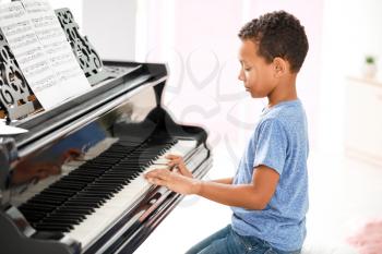 Little African-American boy playing grand piano at home�