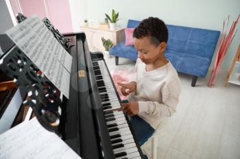 Little African-American boy playing grand piano at home�
