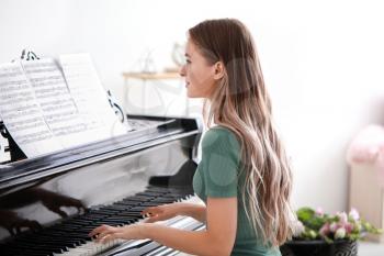 Young woman playing grand piano at home�