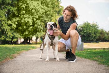 Sporty young man with cute dog in park�