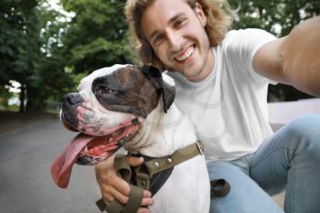 Young man with cute dog taking selfie in park�