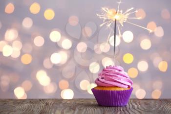 Tasty Birthday cupcake on table against defocused lights�
