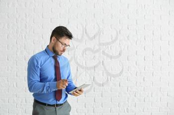 Portrait of businessman with tablet computer against white brick wall�