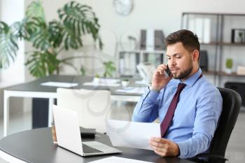 Portrait of businessman talking by phone in office�