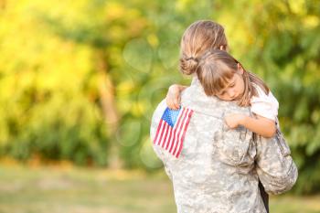 Military man hugging his little daughter outdoors�