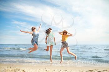 Happy jumping young women on sea beach at resort�