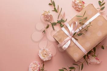 Gift box and beautiful flowers on color background�