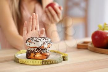 Woman refusing to eat unhealthy donuts, closeup. Diet concept�