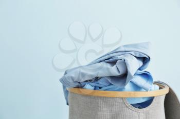 Basket with dirty laundry on color background�