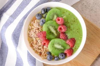 Bowl with tasty oat flakes and fruits on table�