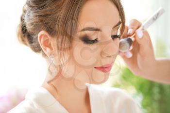 Professional makeup artist working with young bride at home, closeup�
