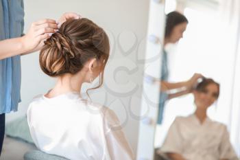 Professional hairdresser working with young bride at home 