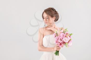 Portrait of beautiful young bride with wedding bouquet on light background�