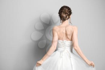 Beautiful young bride on grey background, back view�