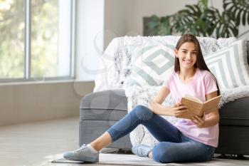 Young girl with book at home�