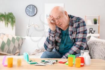 Elderly man with pills at home�