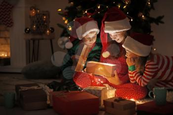 Cute little children opening magic Christmas gift at home�
