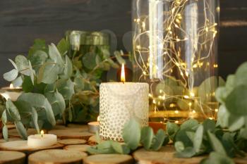 Beautiful burning candles with eucalyptus on table�