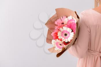 Woman with bouquet of beautiful gerbera flowers on light background�