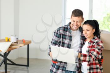 Happy couple with laptop planning design of their new house�