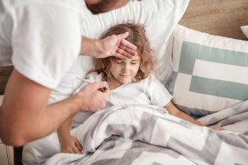 Father measuring temperature of his little daughter ill with flu at home�