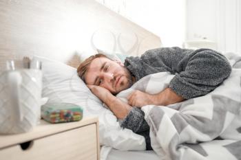 Man ill with flu lying in bed�